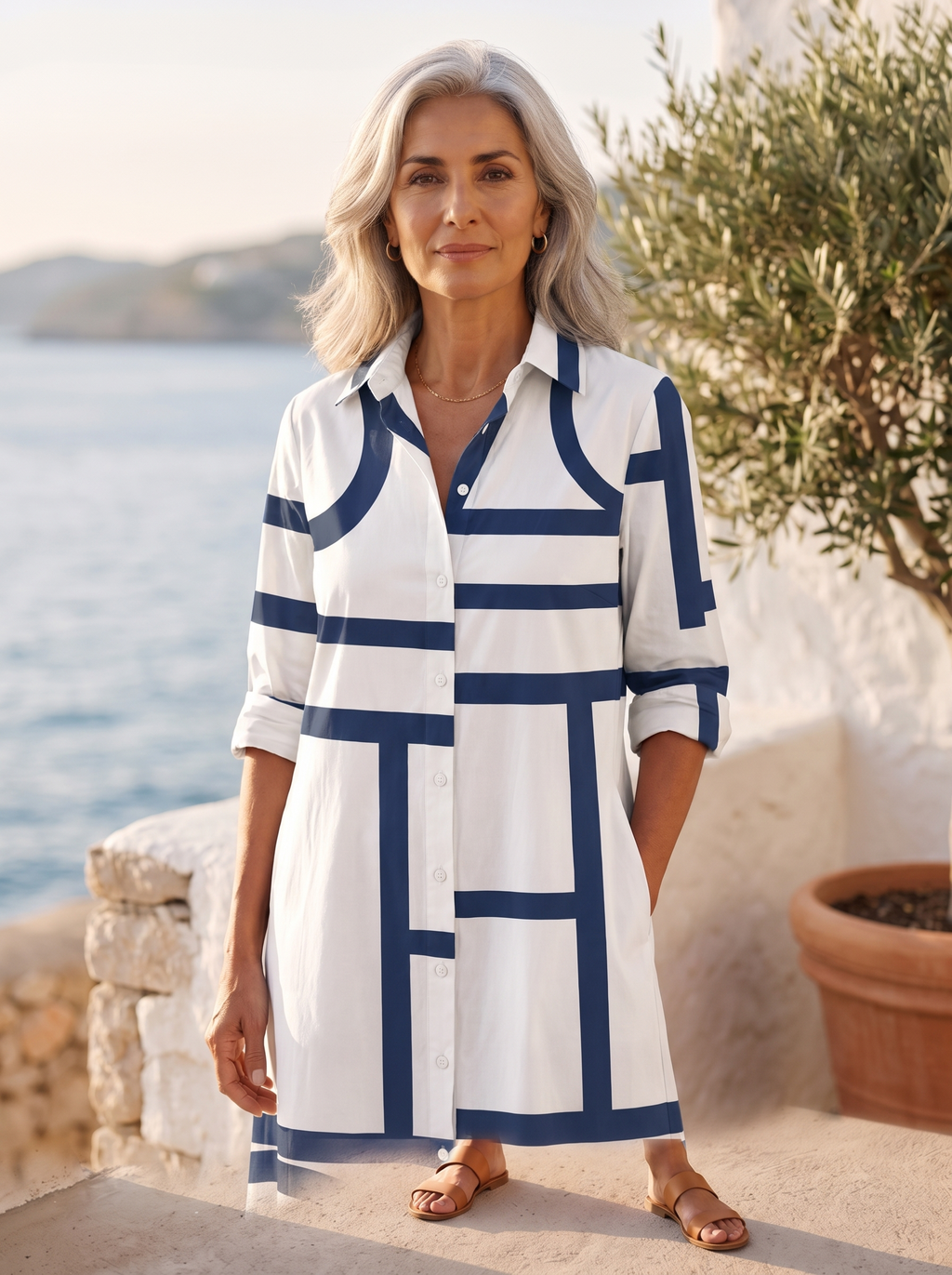 Close detail of the white shirt dress showing the navy geometric line print, classic collar, button placket and rolled sleeve