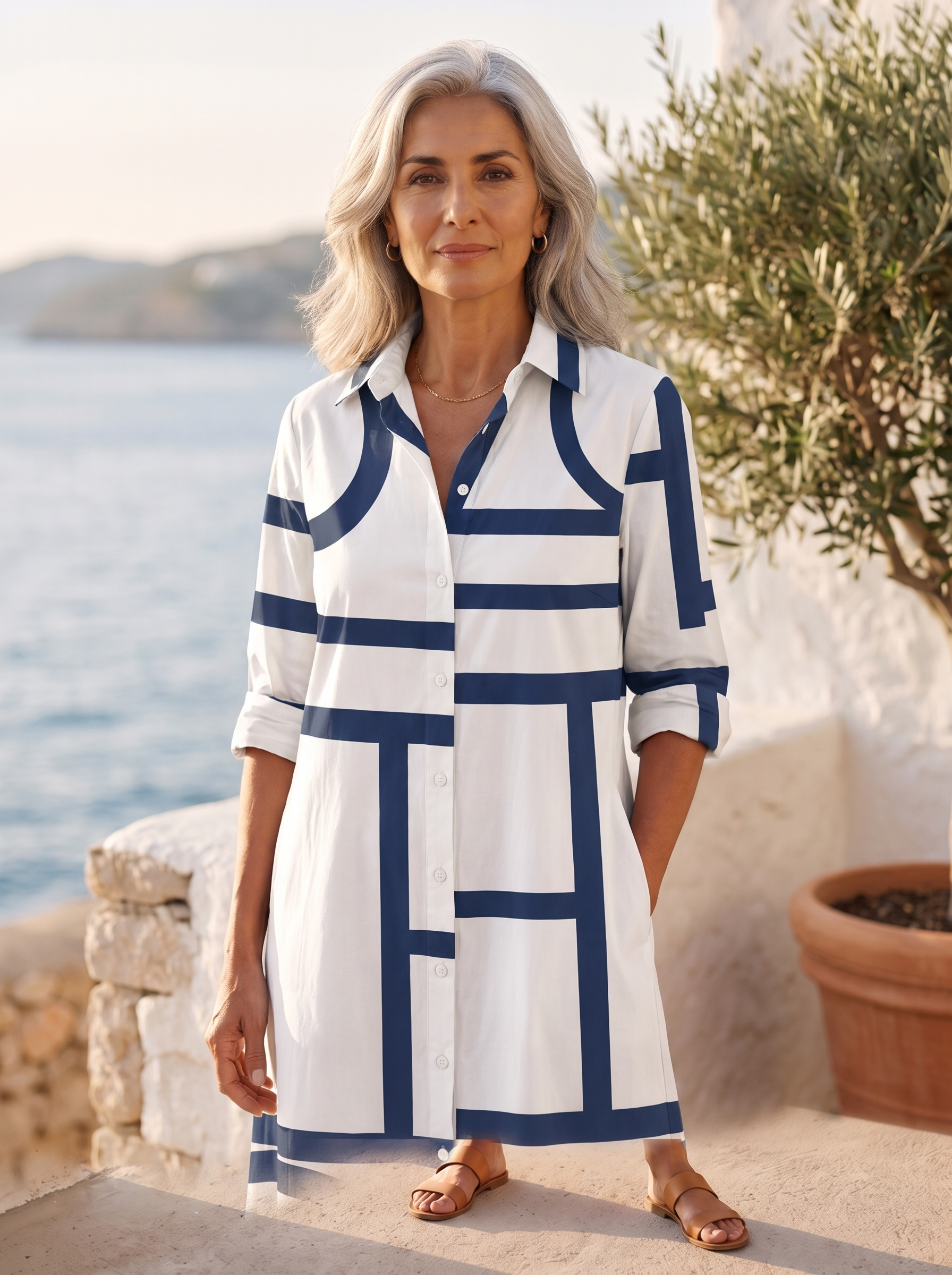 Close detail of the white shirt dress showing the navy geometric line print, classic collar, button placket and rolled sleeve