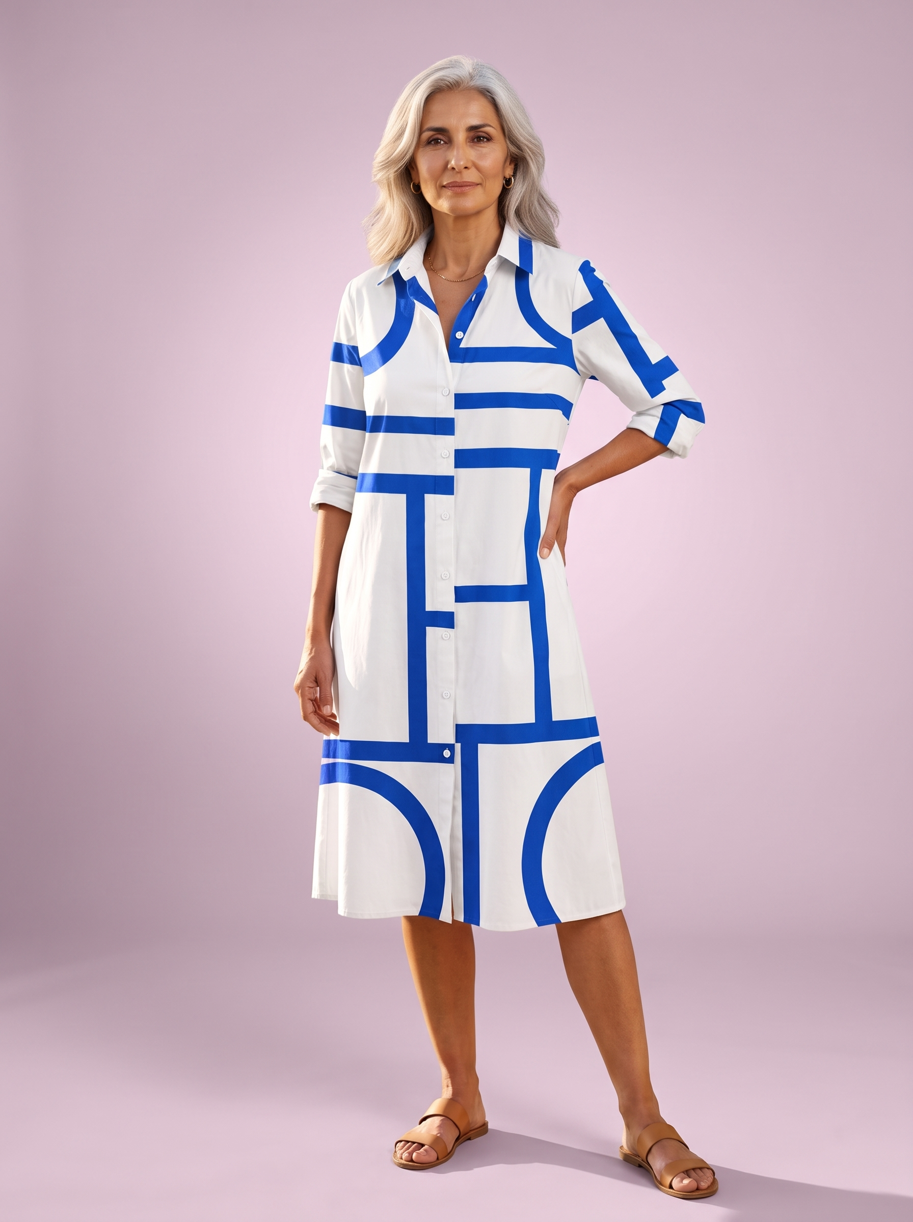 Spanish woman over 50 in the white shirt dress with a bright blue geometric line print, studio shot on a soft lilac backdrop