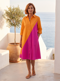 Spanish woman around 50 with an auburn bob on a Mediterranean terrace in the orange and magenta colour-block shirt dress