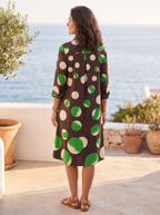 Back view of the chocolate-brown polka-dot shirt dress on a Mediterranean coastal terrace